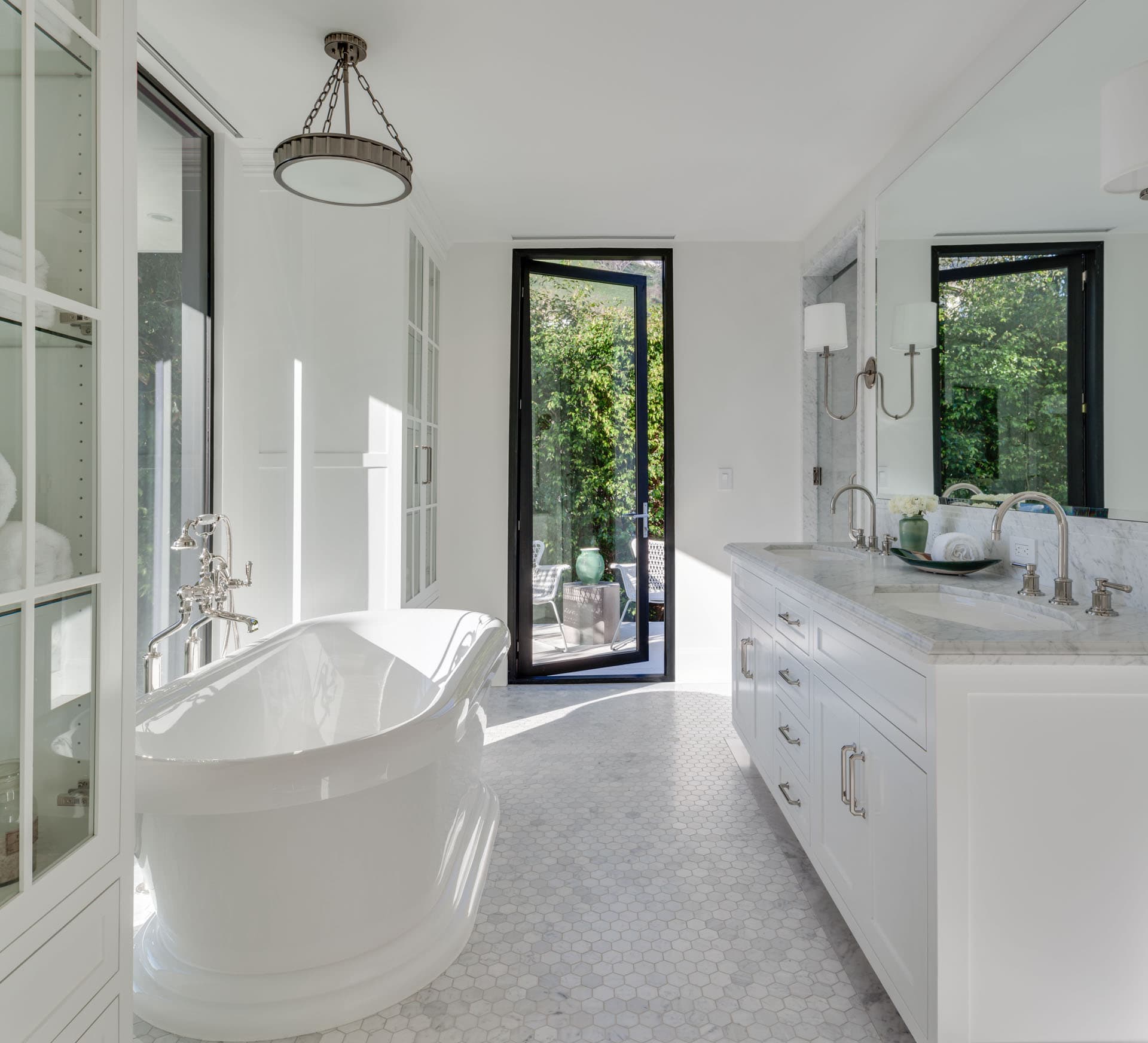 Luxurious white marble bathroom with freestanding tub and garden view