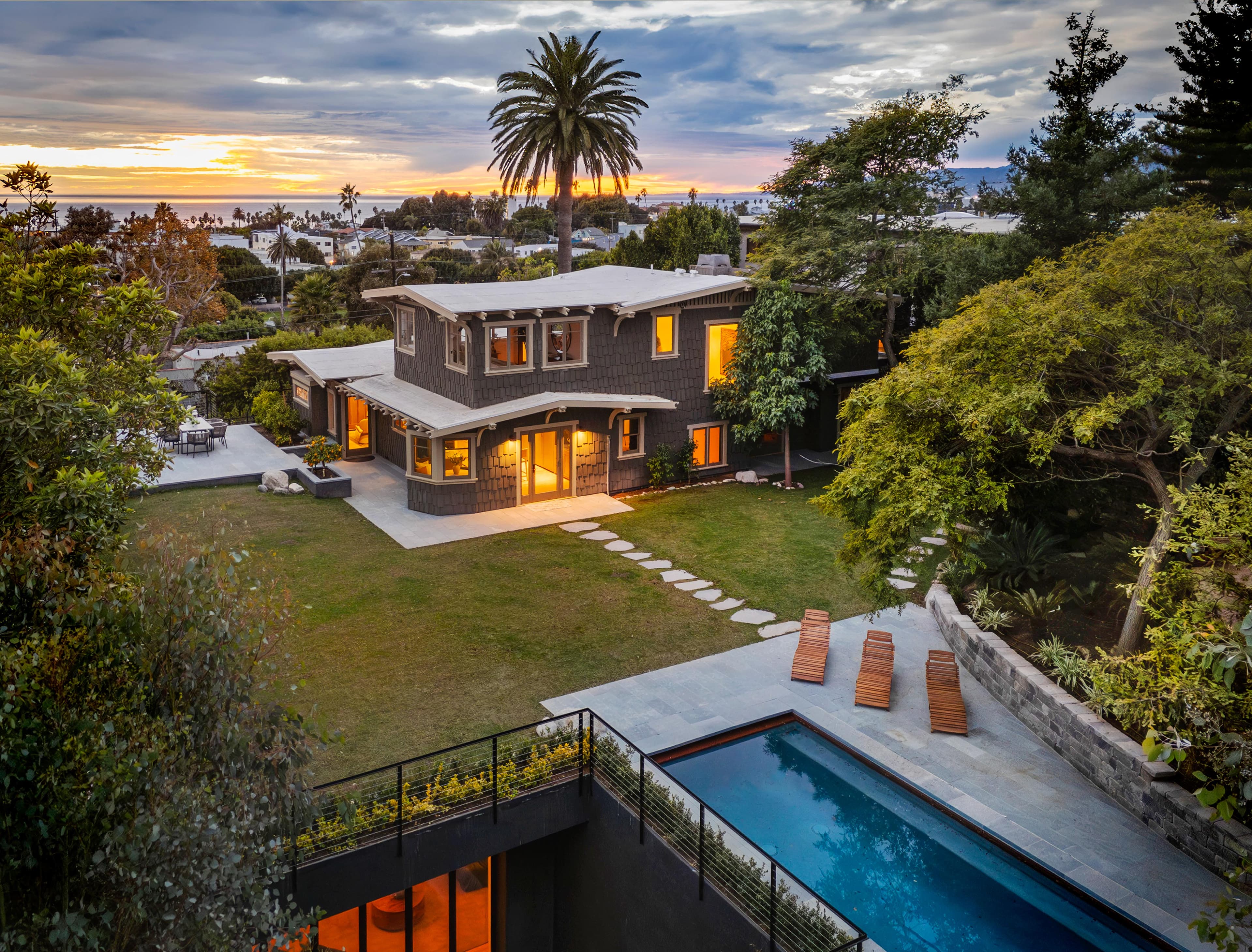 Aerial view of craftsman home at sunset with pool and ocean views